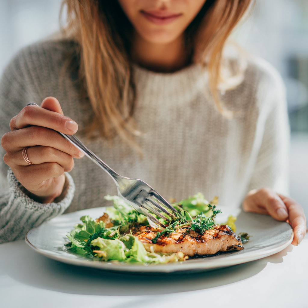 A realistic close-up food photography shot of a woman eating a healthy meal from a plate.